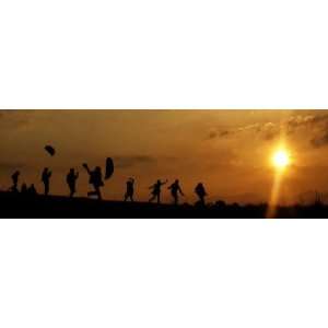 People Fly Kites as They are Silhouetted by the Setting Sun on 