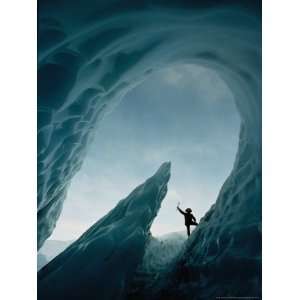 Climber Raises His Ax in Triumph Near the Opening of an Ice Cave 